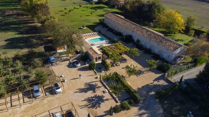 Vue aérienne d'une propriété avec piscine, jardins et plusieurs bâtiments.